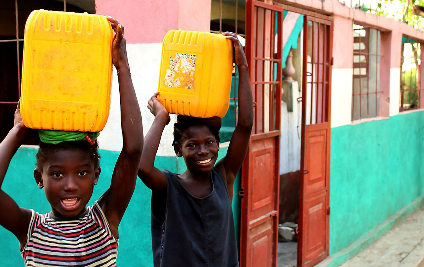 Crianças carregam água no Haiti. Foto: David Greenwood Haigh